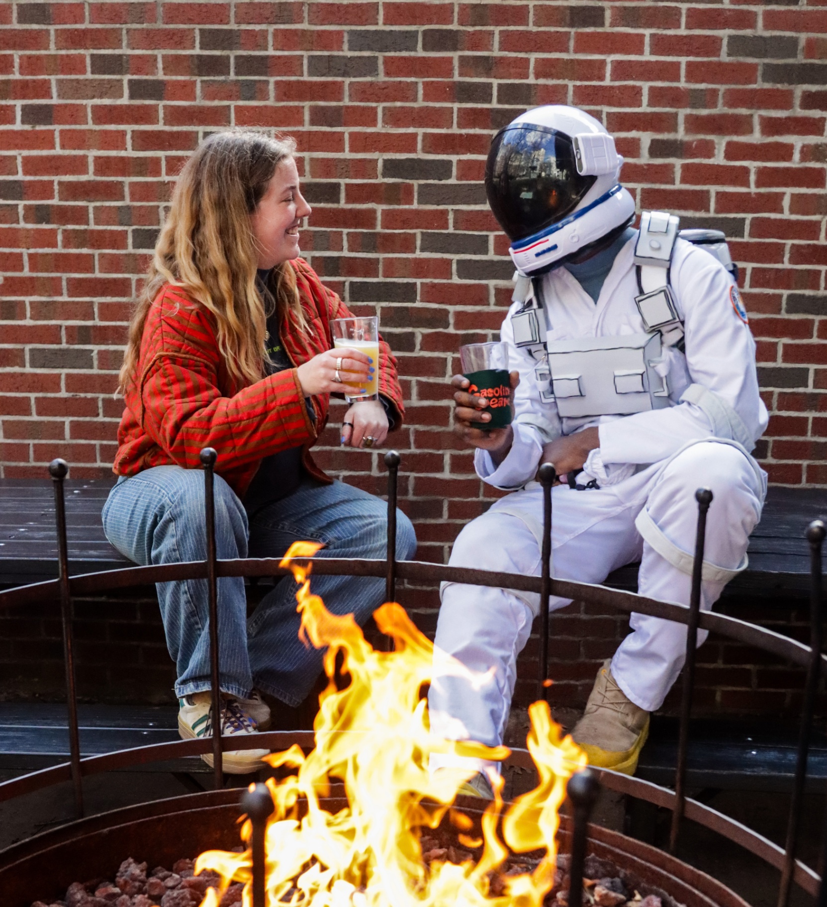 Hopstronaut sharing a beer with a friend around a fire pit