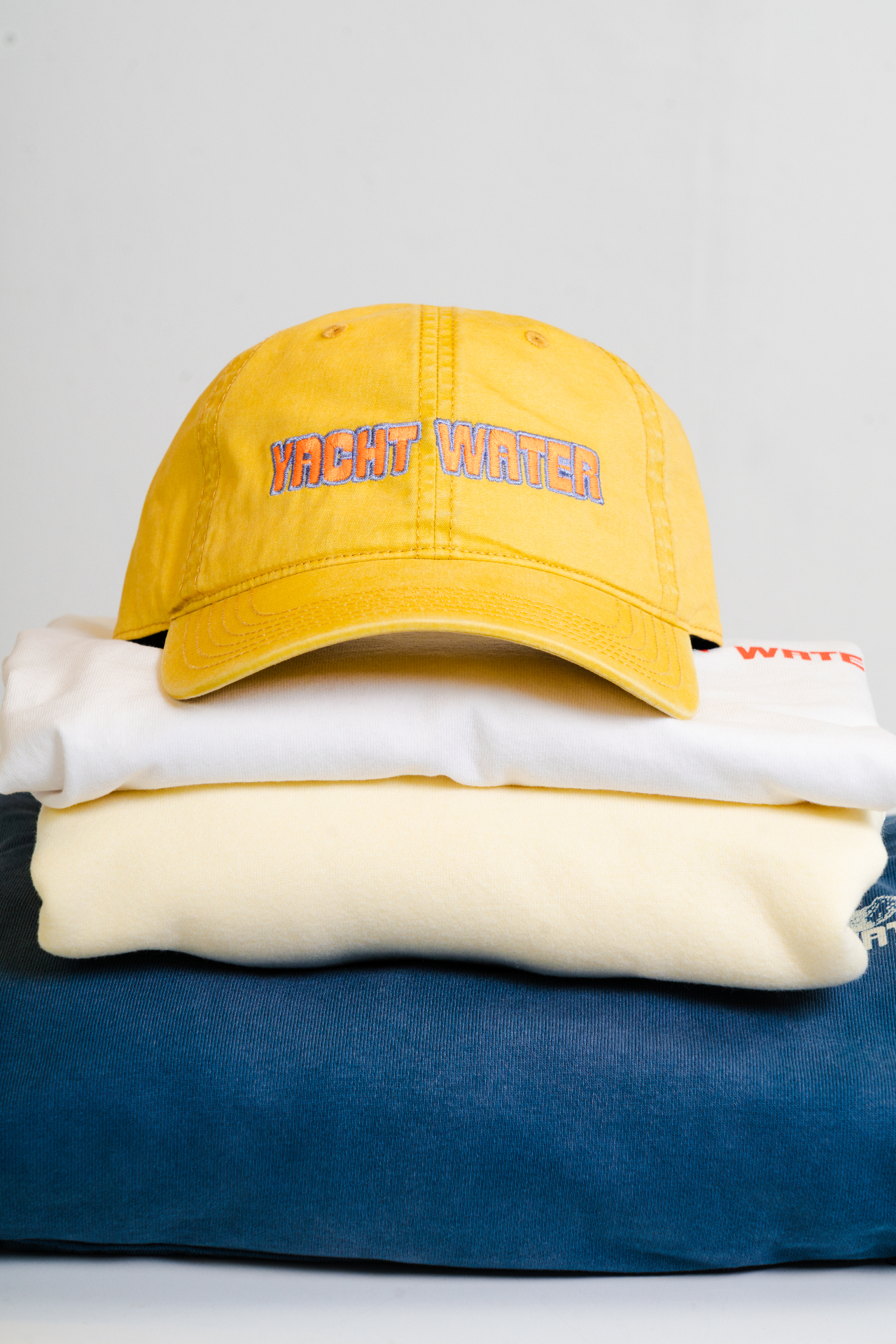 Yacht Water merch stack with hat and folded apparel